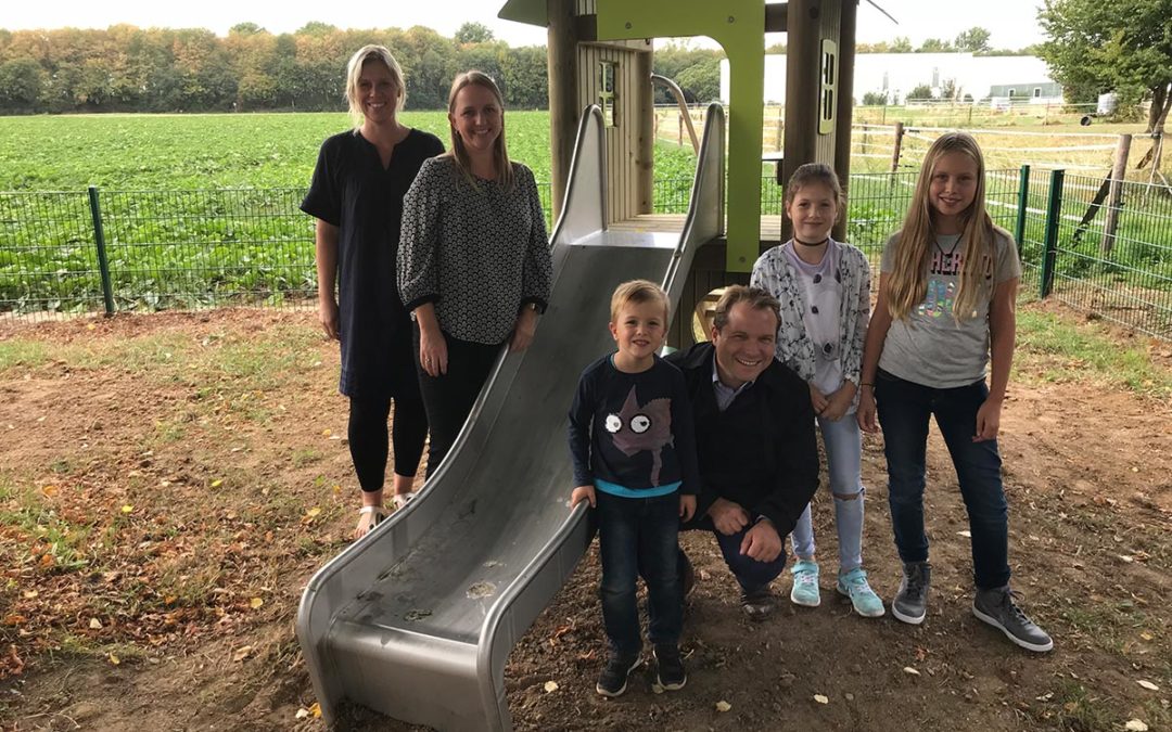 Bürgermeister Dr. Martin Mertens freut sich mit Kindern und Eltern über neue Spielplatzausstattung