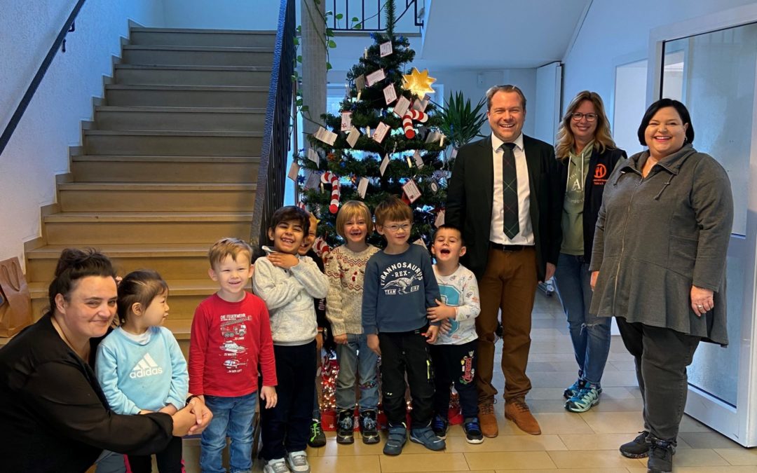 Bürgermeister und Kinder der Kita Sonnenhaus schmücken den Weihnachtswunschbaum der Tafel